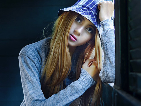 A picture in blue colours of a girl leaning on a window sill.